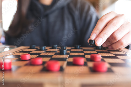 Closeup image of people playing and moving checkers in a chessboard