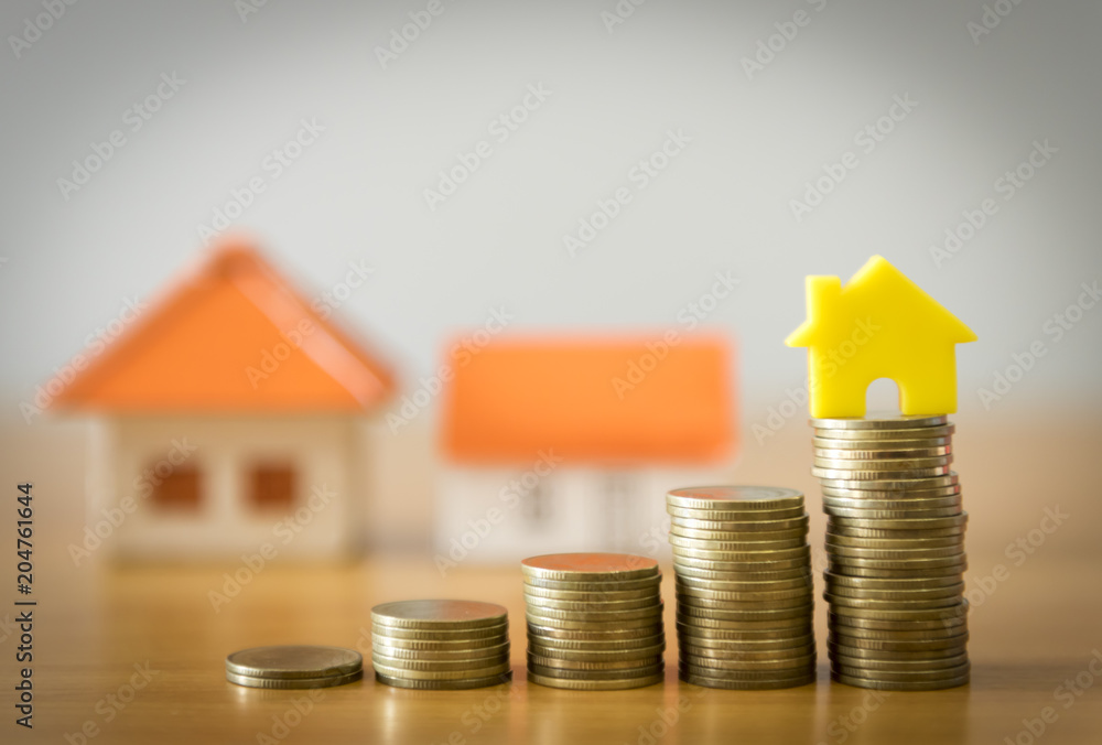 Home model on the growing coin stack for concept of money saving for home buying fund Home model on the growing coin stack for concept of money saving for home buying fund