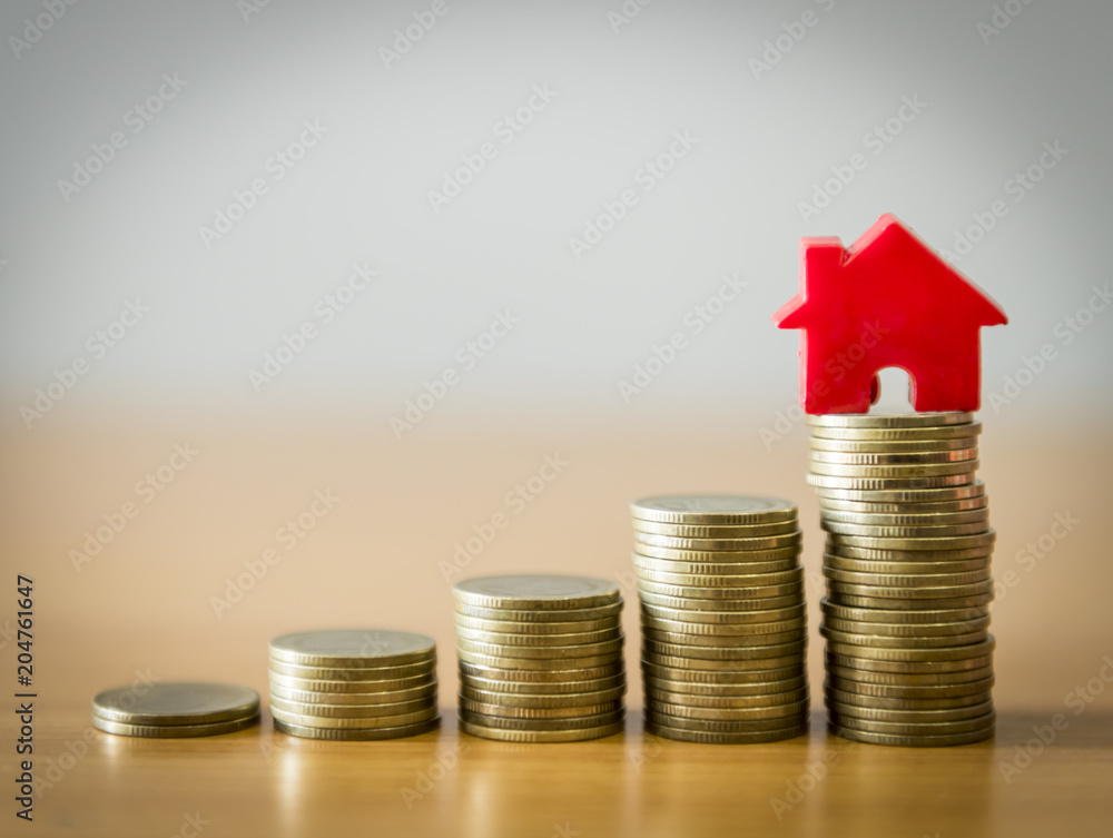 Home model on the growing coin stack for concept of money saving for home buying fund Home model on the growing coin stack for concept of money saving for home buying fund