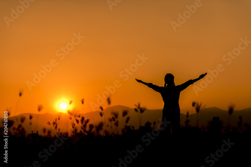 Silhouette happy woman standing on a sunset