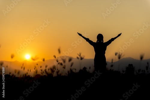 Silhouette woman at sunset standing elated with arms raised up above her head. © Photo Market