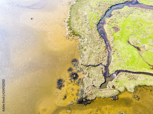 Fototapeta Naklejka Na Ścianę i Meble -  Aerial view of the Glaslyn Marshes close to the railway with the Snowdonia mountain range national park in background - Porthmadog, Wales - United Kingdom
