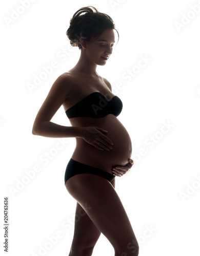 Silhouette of pregnant woman touching her belly on white background. Pregnancy, maternity, preparation and expectation concept
