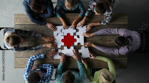 Business people and puzzle on wooden table, teamwork concept