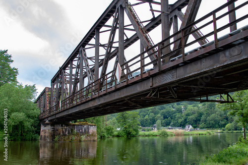 Rusty metal train bridge over a small river 