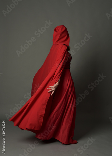 Принти на полотні full length portrait of woman wearing red fantasy costume with cloak, standing pose on grey studio background