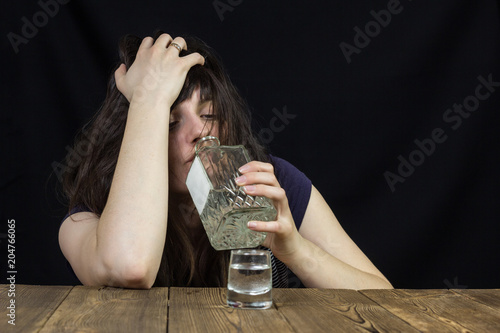 drunk girl uses alcohol on a black background, female alcoholism