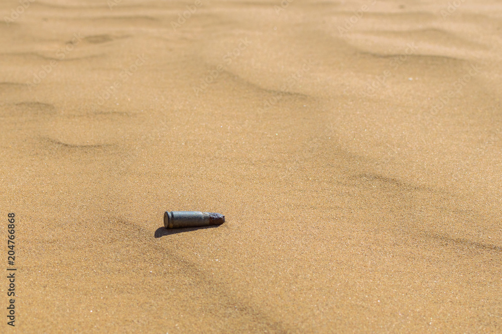 Old rusty bullet cartridge case in sand close. Concept: armed conflicts in the Middle East Old rusty bullet cartridge case in sand close. Concept: armed conflicts in the Middle East