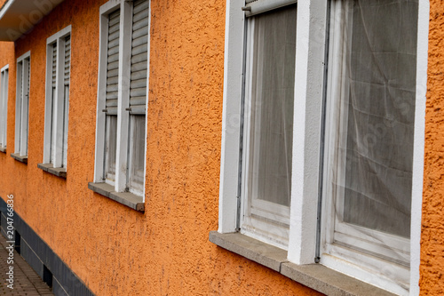 Orange house facade with windows and shutters 