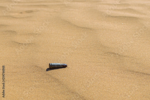 Old rusty bullet cartridge case in sand close. Concept: armed conflicts in the Middle East photo