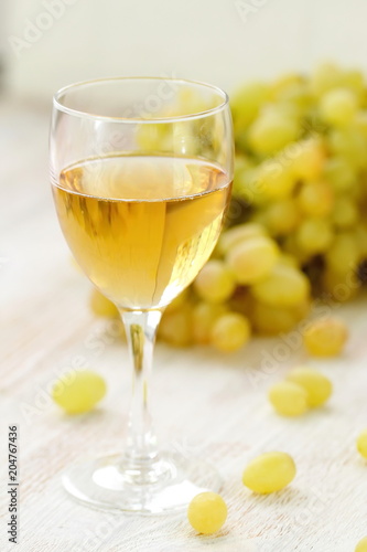 Glass of wine and grapes in the basket on a wooden table.