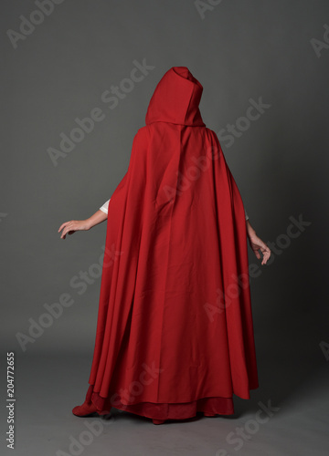 Foto full length portrait of woman wearing red fantasy costume with cloak, standing pose on grey studio background