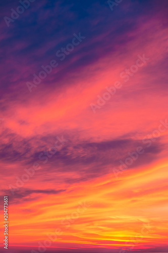 Beautiful cloudscape at scarlet sunset with colorful contrasting cirrus clouds 