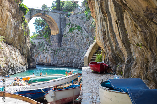 Fototapeta Naklejka Na Ścianę i Meble -  Fiordo di Furore beach. Furore Fjord Amalfi Coast Positano Naples Italy. - Fishermen colored boats on the beach, under the bridge of the fjord. The turquoise water of the beach.