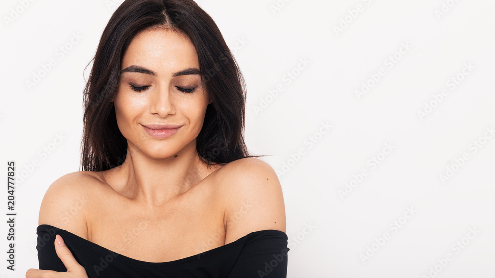 Front view of a fashionable brunette woman standing in studio with her eyes closed Front view of a fashionable brunette woman standing in studio with her eyes closed