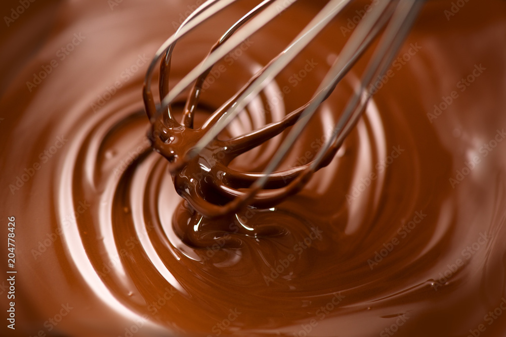Chocolate. Mixing melted dark chocolate with a whisk. Closeup of liquid hot chocolate swirl. Confectionery Chocolate. Mixing melted dark chocolate with a whisk. Closeup of liquid hot chocolate swirl. Confectionery