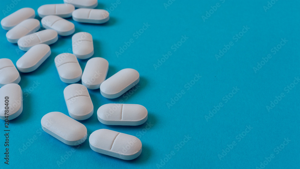 White Oval pills on blue background. Medicine and healthy