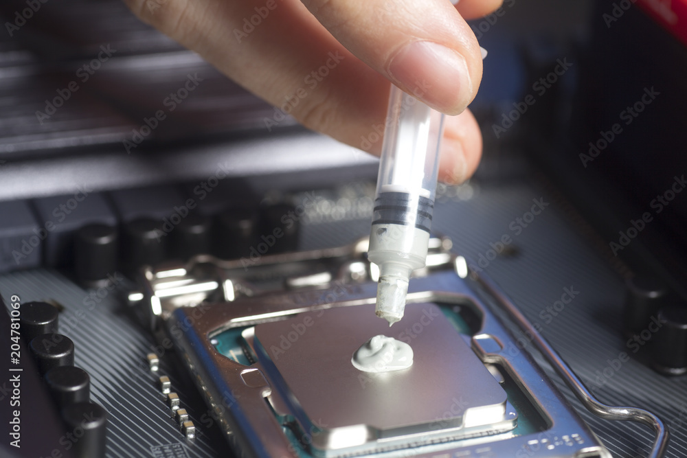 Hand with syringe applying thermal paste on the CPU processor on motherboard Hand with syringe applying thermal paste on the CPU processor on motherboard