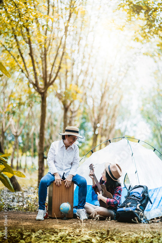 camping concept mom and daughter happy travel together with ukelele and sing in forest autumn landscape background