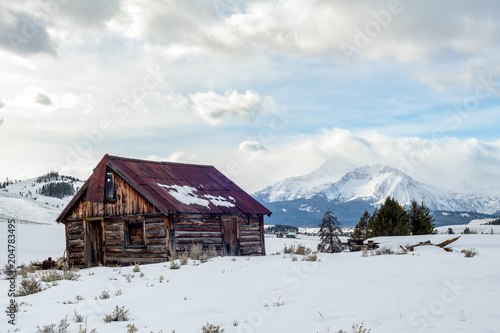Rickety old cabin new Stanley Idaho in winter with Sawtooth Mountain range