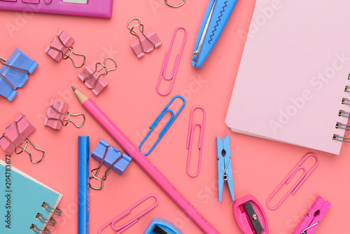 Stationary concept, Flat Lay top view Photo of Scissors, pencils, paper clips,calculator,sticky note,stapler and notepad in pink and blue tone on pink background with copy space