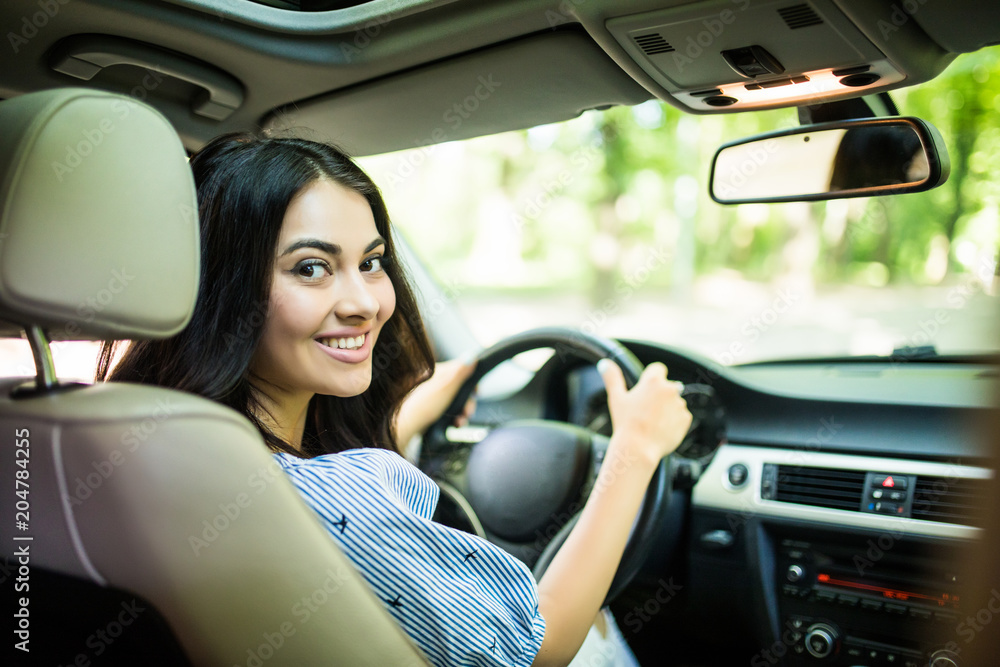 Portrait of beautiful smiling woman driving a car on street