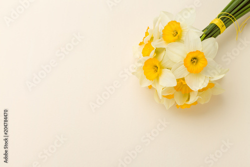 Fototapeta Naklejka Na Ścianę i Meble -  White daffodil bouquet on yellow pastel background with copy space.