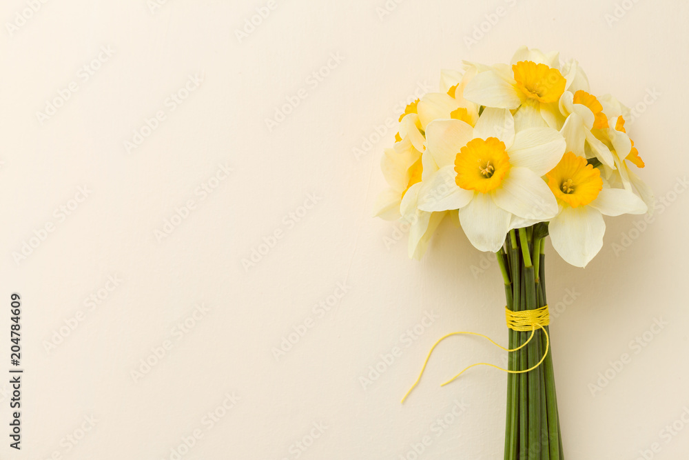 White daffodil bouquet on yellow pastel background with copy space