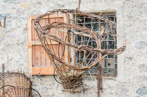 An old gerla hanging in front of a window of a mountain shelter. It is an old wooden basket used in the past to transport hay by farmers in the Alps