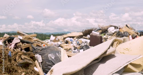 Close up of a man throwing old carpeting in a landfill