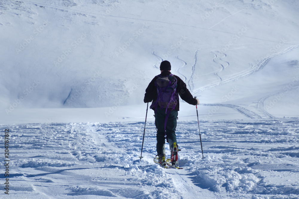 One man walking with ski over the snow land to the mountain view from back One man walking with ski over the snow land to the mountain view from back