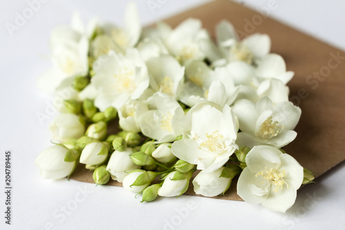 Sprigs of jasmine in postal envelope on white background close up. copy space. spring mood. mother's day. the freshness of flowers.The inscription on the letter -happy. DOF focus.