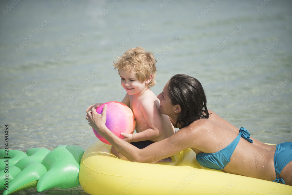 Φωτογραφία mother with child play ball on air mattress in the watere in the summer