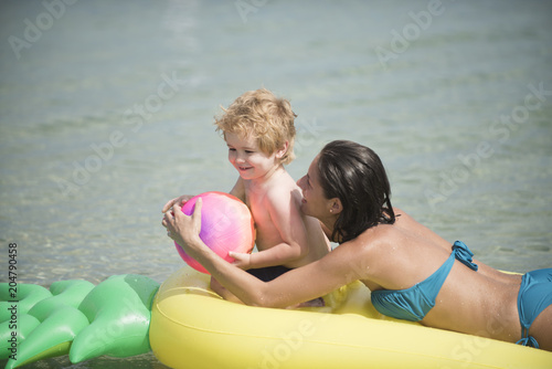 mother with child play ball on air mattress in the watere in the summer. photo
