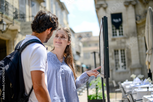 Photography cheerful young couple looking at restaurant menu on a cultural weekend city trip