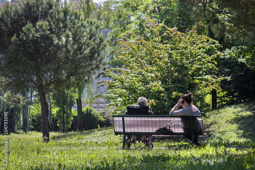old woman with caretaker, the couple sitting at the park 