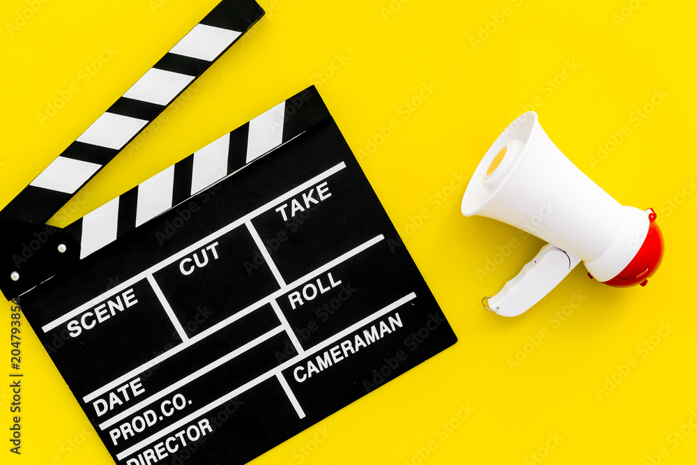 Naklejka premium Film director, producer concept. Filming. Electronic megaphone and clapperbord on yellow background top view