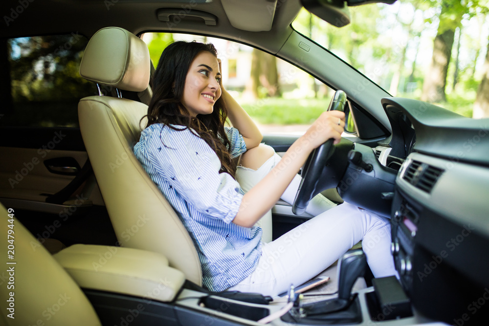 Young woman ooking over her shoulder while driving a car Young woman ooking over her shoulder while driving a car