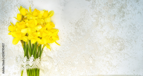 Fototapeta Naklejka Na Ścianę i Meble -  narcissus bouguet with lace laying on the grey cement background, top view with copy space