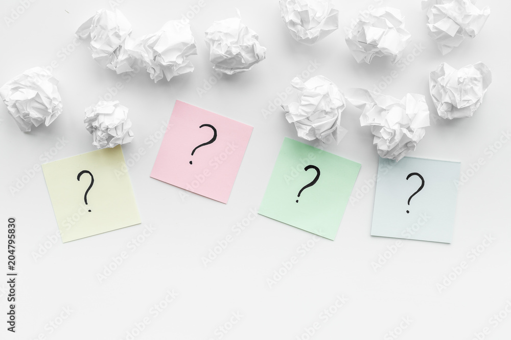 FAQ concept. Question mark on sticky notes near crumpled paper on white background top view copy space FAQ concept. Question mark on sticky notes near crumpled paper on white background top view copy space