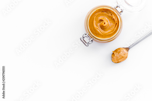 Nut butter  peanut butter in glass jar and spoon with butter on white background top view copy space