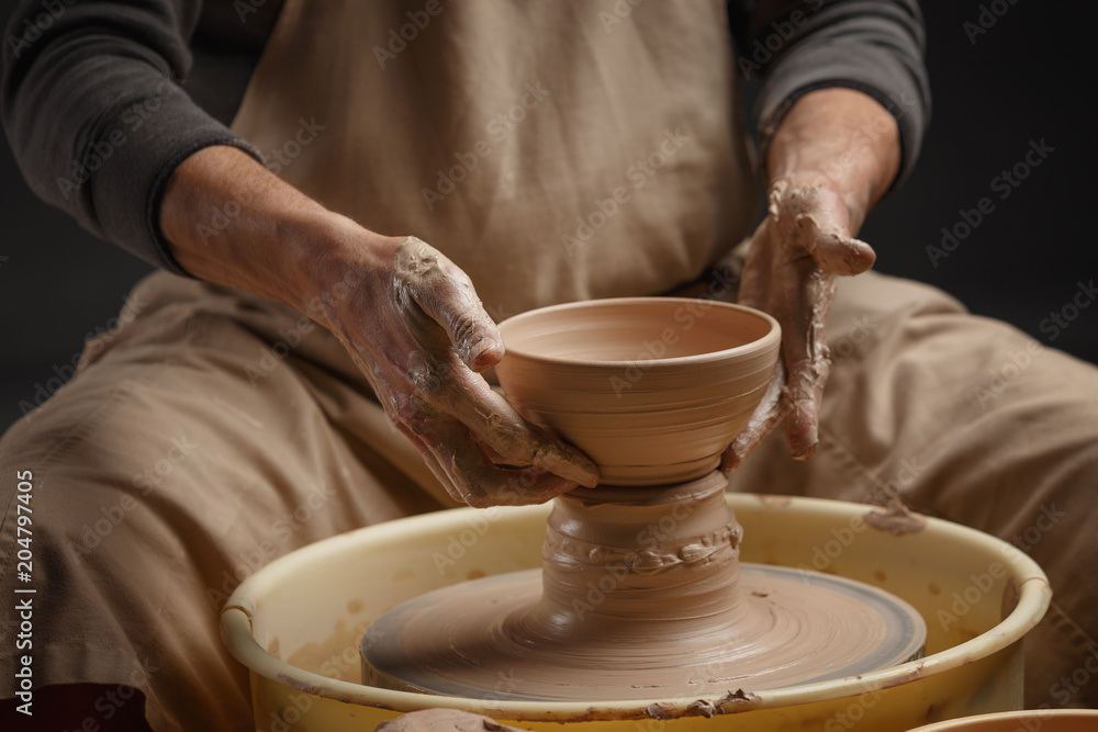Hands of a potter, creating a ceramic pot on the pottery wheel Hands of a potter, creating a ceramic pot on the pottery wheel