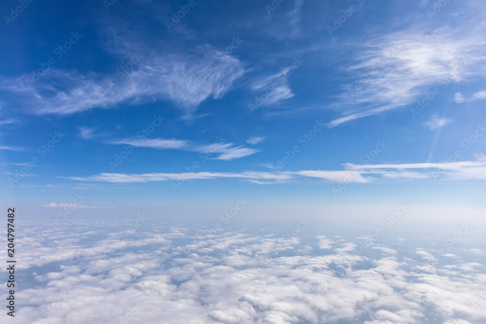 Fototapeta premium View from the airplane to the sky above the Alps mountains. Blue sky with clouds. Background.