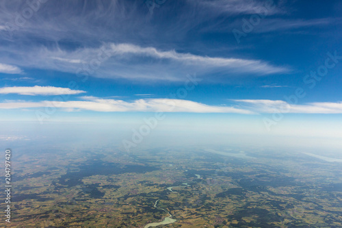 View from the airplane to the sky above the Alps mountains. Blue sky with clouds. Background.