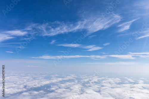 View from the airplane to the sky above the Alps mountains. Blue sky with clouds. Background.