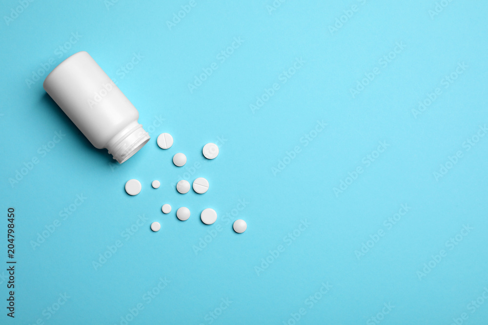 Container with white pills on color background, flat lay