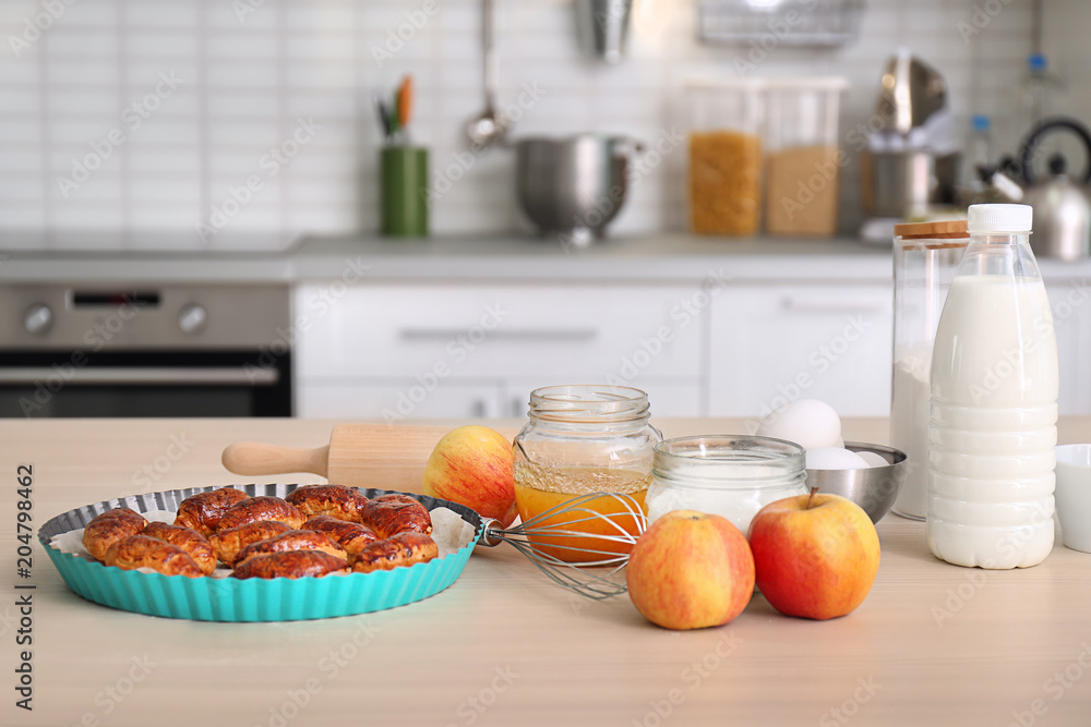 Baking dish with delicious croissants and products on kitchen table Baking dish with delicious croissants and products on kitchen table