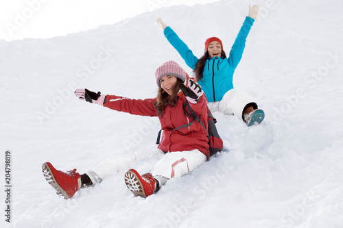 Happy women sliding down the snowy hill. Winter vacation