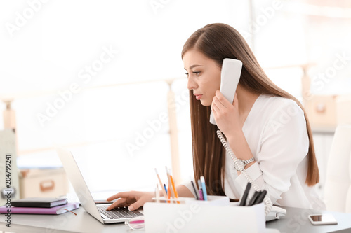 Young woman talking on phone at workplace