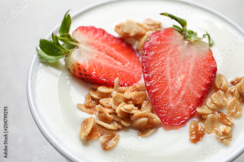 Bowl with tasty yogurt, strawberry and granola, closeup